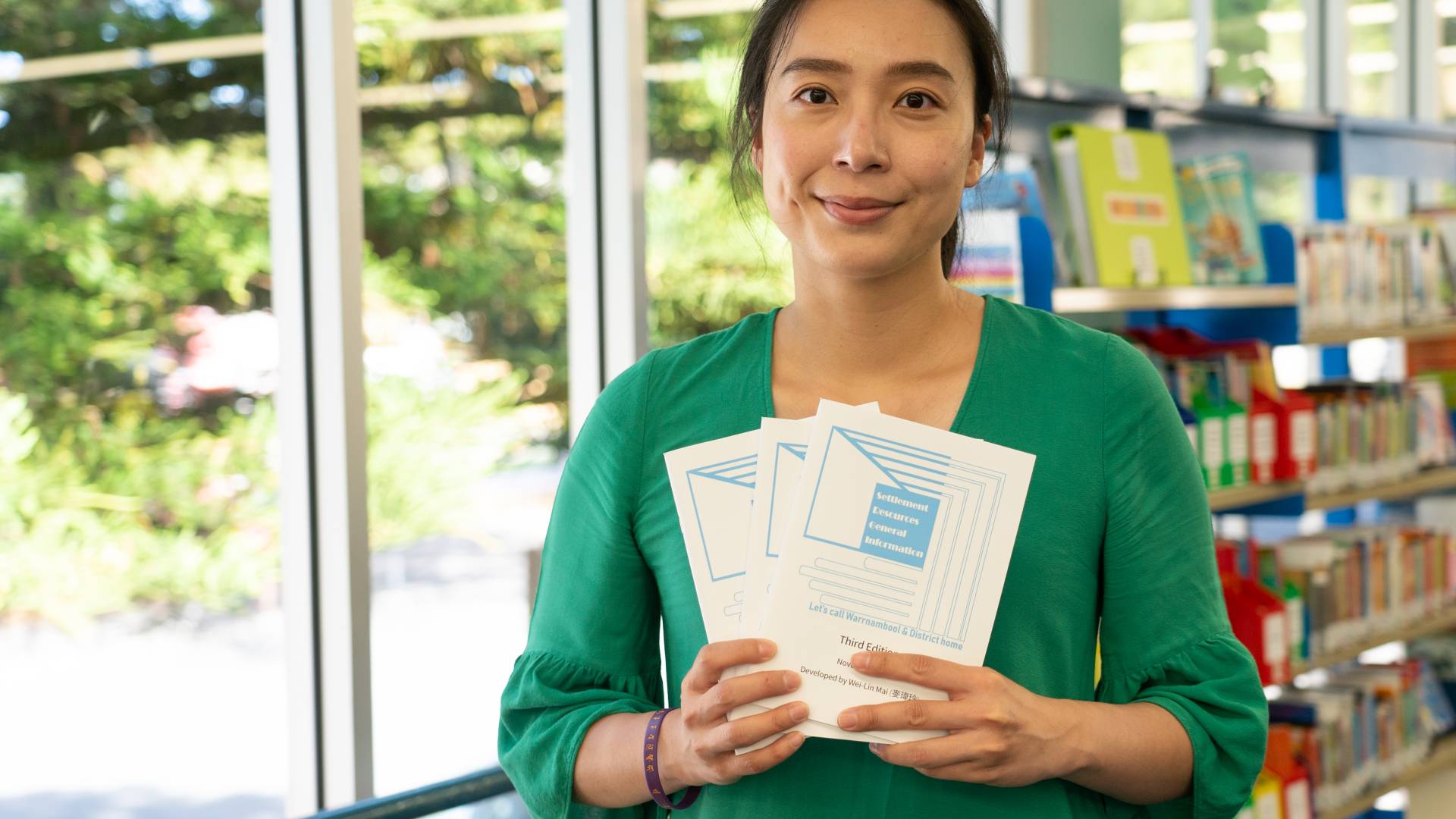 Wei-Lin Mai with the third edition of her Migrant Settlement Resources Guide.