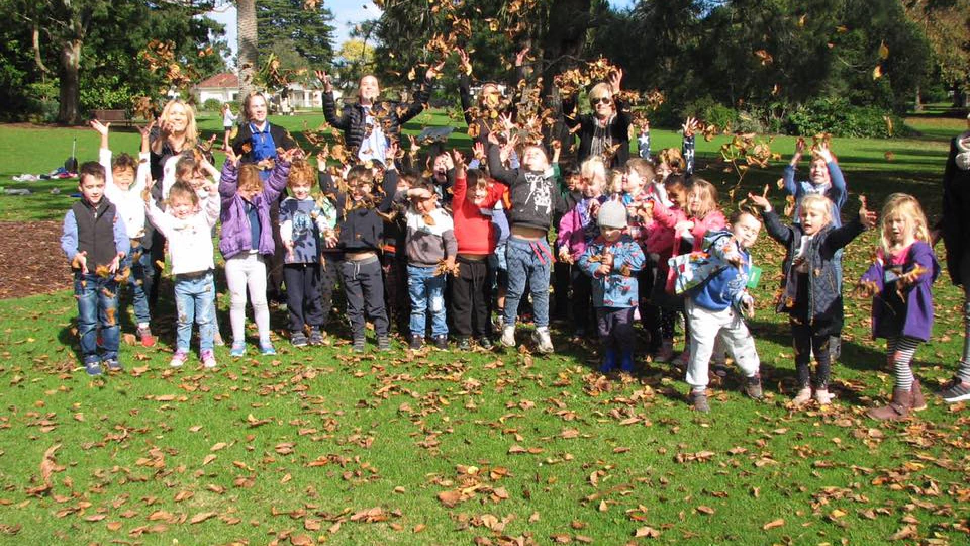 Children throwing autumn leaves into the air.