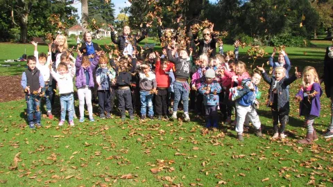 Children throwing autumn leaves into the air.