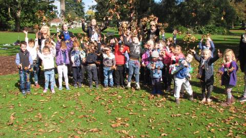 Children throwing autumn leaves into the air.